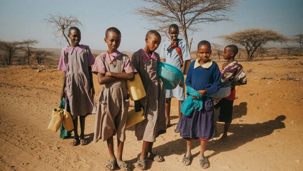 School girls walking long distance to get water from dried river bed