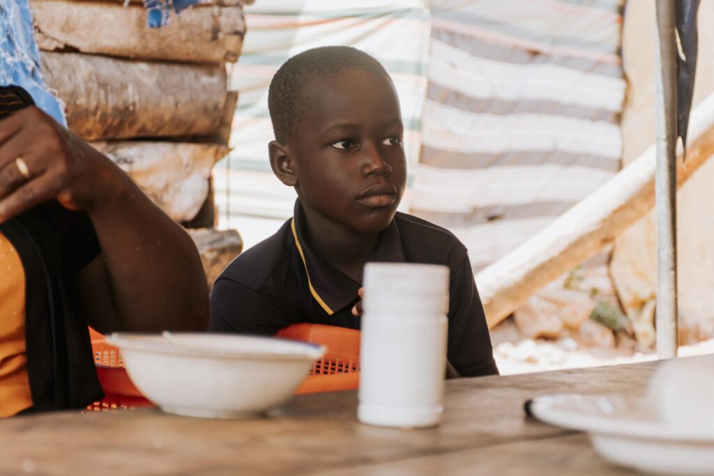 Kid sitting at community table with plate and cup