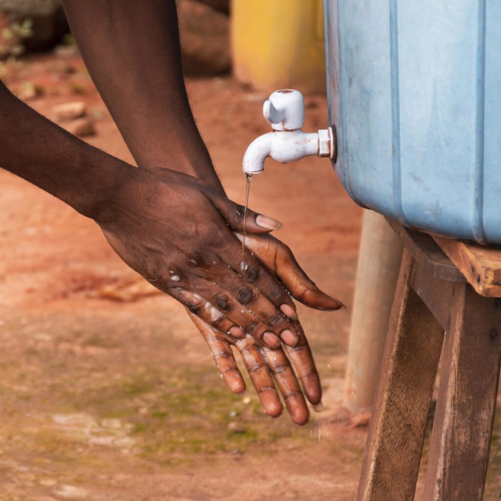 Woman washing hands from a water tank